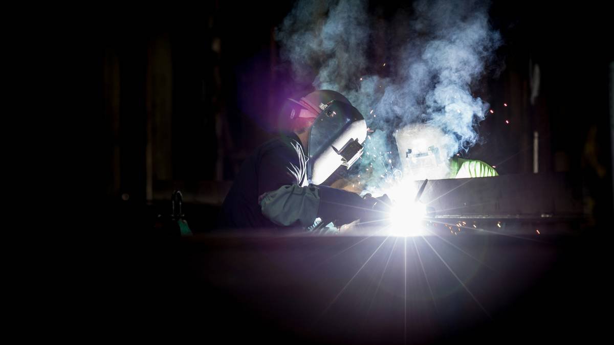 Technician preparing metal edges cut with plasma cutter for welding with plasma cutter workflow