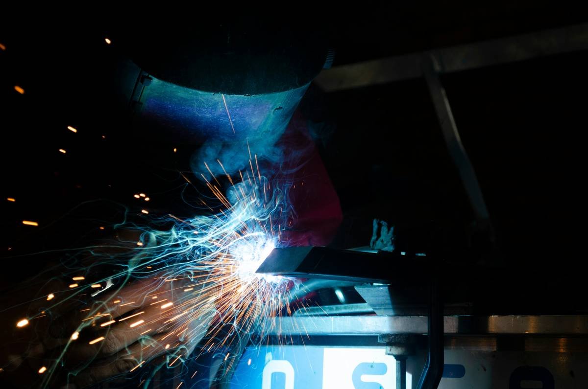 Professional using a welder with plasma cutter on steel fabrication project